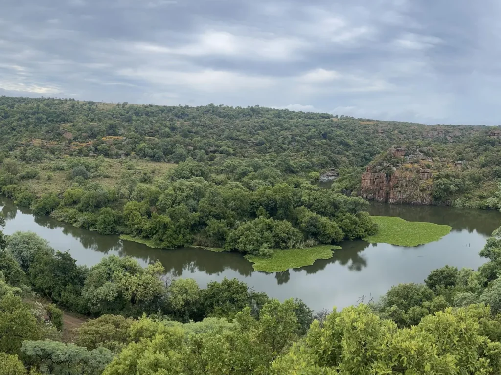 Scenic view of the Wilge River flowing through Angels Valley Lodge near Balmoral, surrounded by lush green bushveld and rocky cliffs.